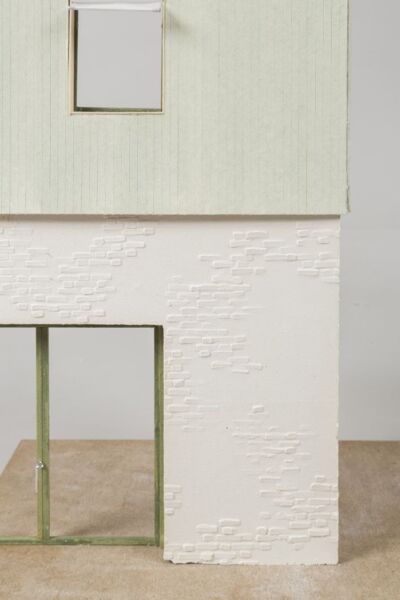 Ein Foto eines farbigen Modells mit weißem geziegelten Erdgeschoß, Salbei farbenen hölzernen 1. Obergeschoß. Grüne Fensterrahmen.