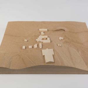 A model photo of an urban planning model of a small settlement on a flat 3D terrain. MDF, wood.