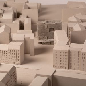 A close-up of an urban planning model of a dense urban area with an inserted project that stands out due to a different structure. Grayboard.