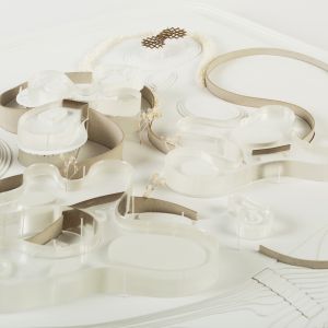 A detail photo of an urban planning model. Base made of Bristol board, free-form buildings made of acrylic, walls made of grayboard.