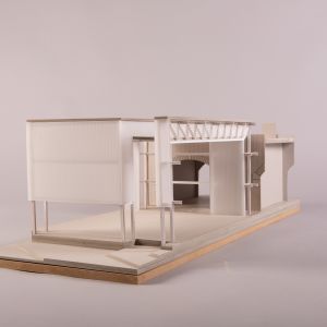A photo of a sectional model in a small scale with wrapped I-beams, trusses, and an arcade made of bricks. MDF, greyboard, wood, polypropylene.