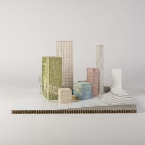A model photo of an urban planning model of a small colorful settlement with high-rise buildings on a flat 3D terrain. Various cardboard materials.