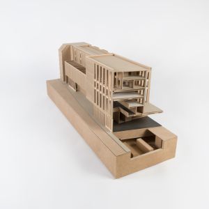 A model photo of a tenement building on a base, transversely cut. MDF, grayboard.