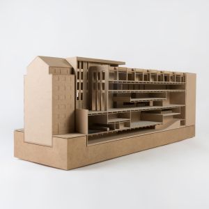 A model photo of a tenement building on a base, longitudinally cut. MDF, grayboard.