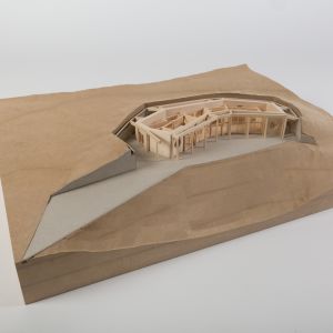 A model photo of a building sunken into a site. MDF, grayboard, wood. Lightweight construction.